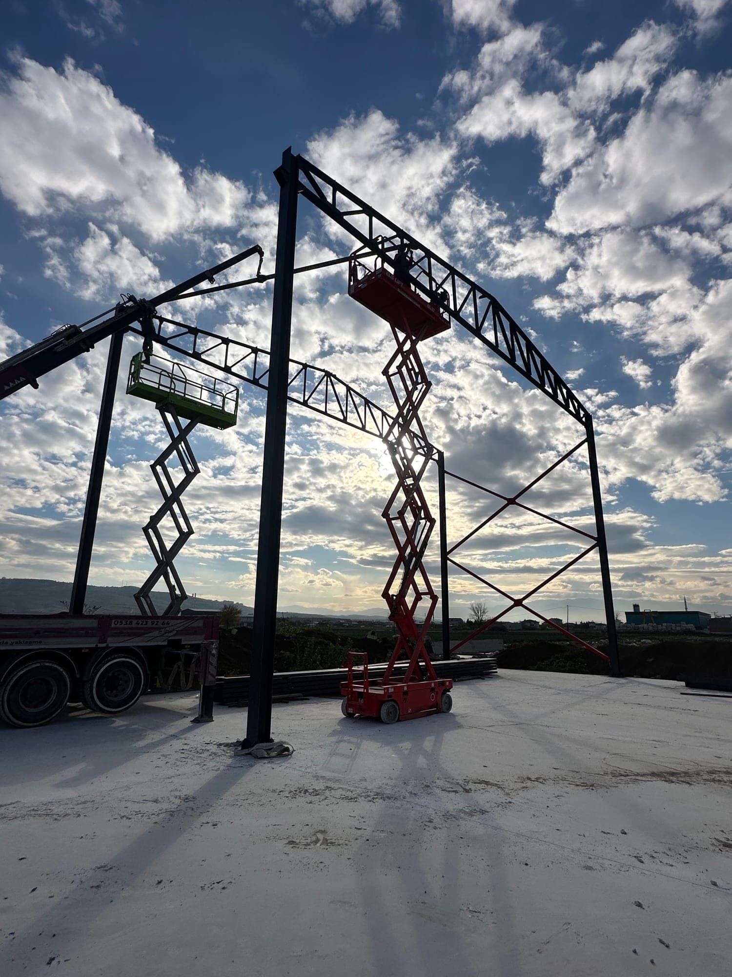 Steel portal frame being erected on site with access platforms